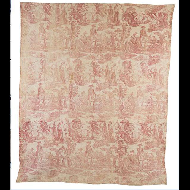 A color photograph of a hand-stitched quilt. The quilt top is pink and tan, and was copper-printed with scenes featuring Benjamin Franklin and George Washington leading the Colonies to freedom. 